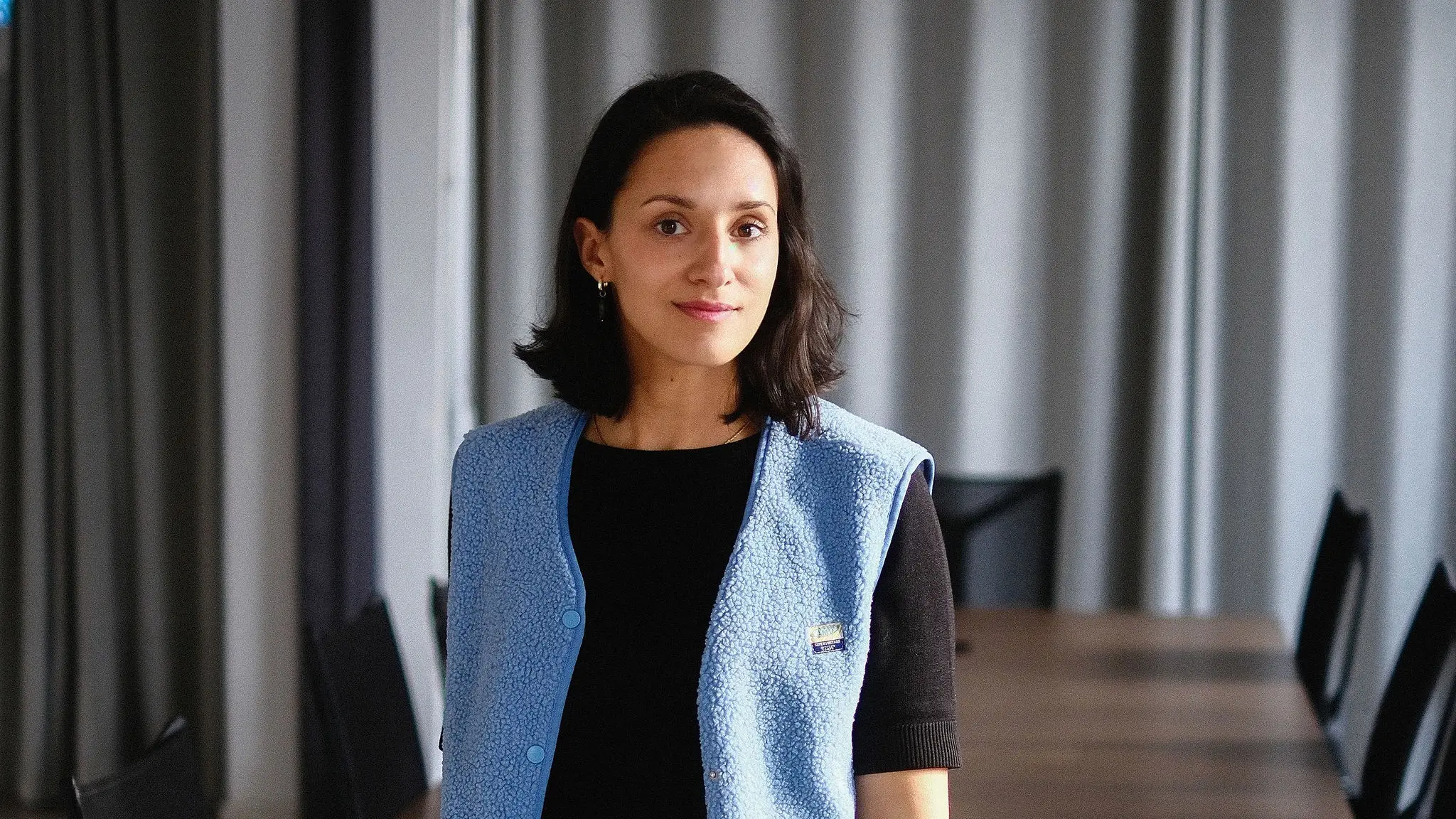 Jamaine Pulat standing at the head of a long meeting table in a bright office